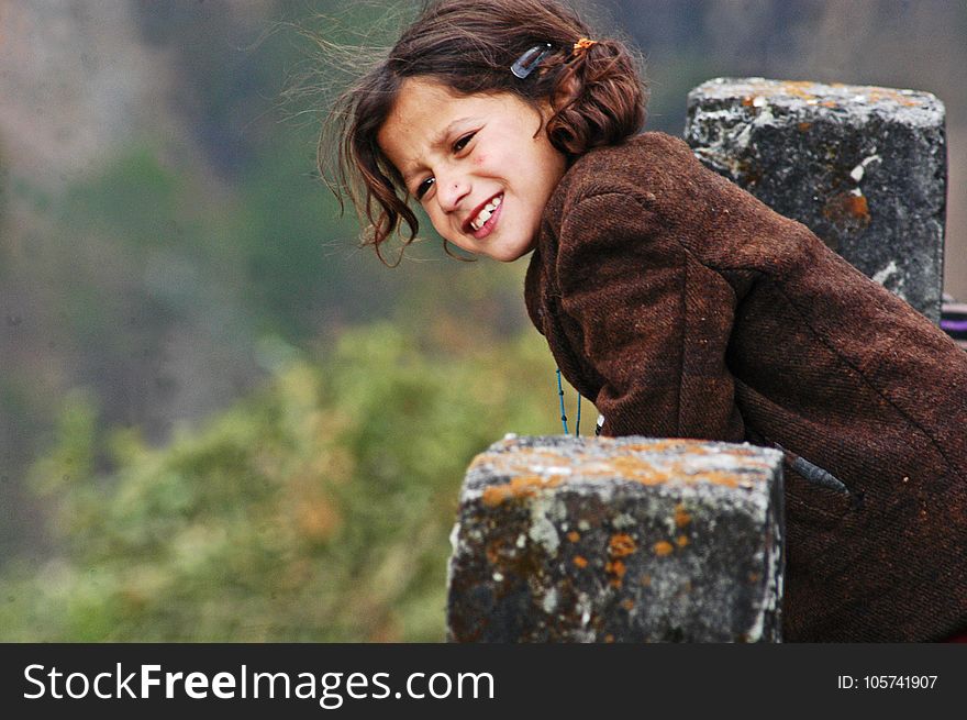Girl Wearing Brown Coat Leaning On Concrete Pillar