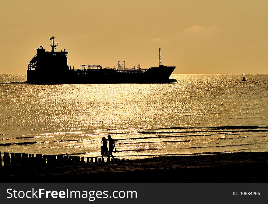 During sunset a ship passes the Dutch coast.