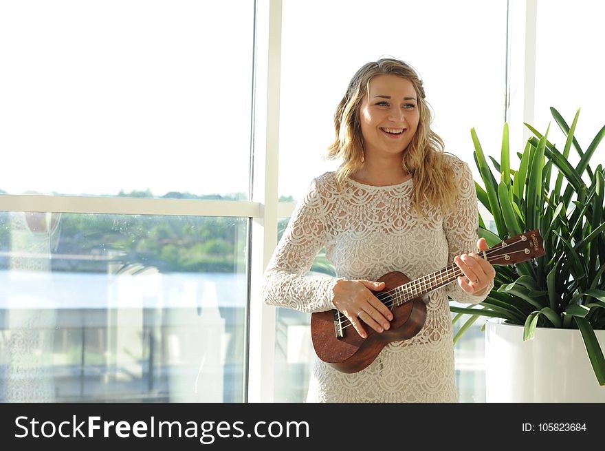 Woman Wearing White Floral Dress Playing Ukulele