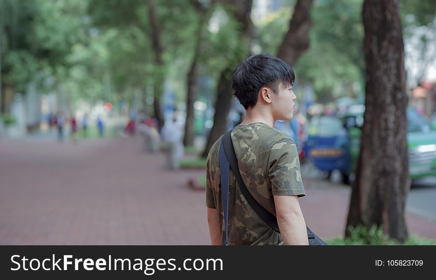 Man In Green And Grey Camouflage Shirt While Standing Behind Tree