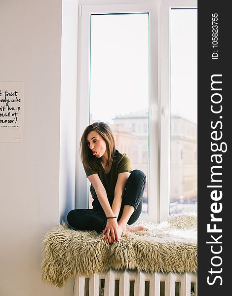 Woman In Green Shirt And Black Denim Jeans Sitting Near Window Inside Room