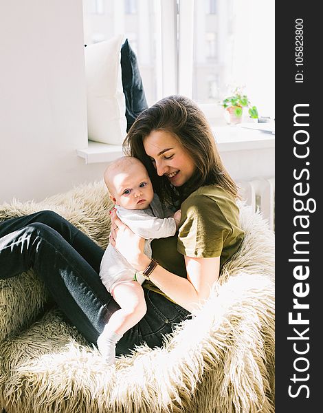 Woman in Green Shirt Holding Baby While Sitting