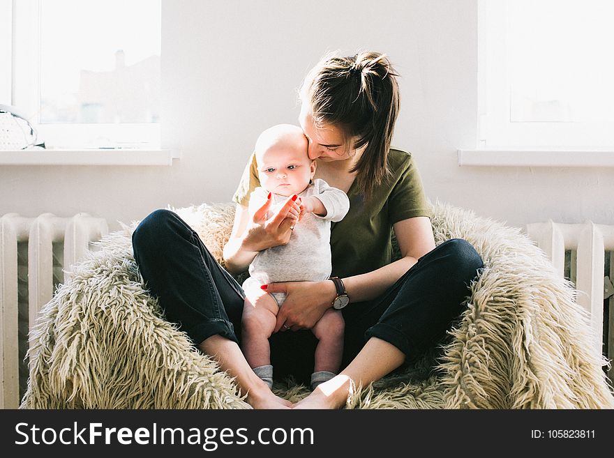 Woman Holding Baby While Sitting On Fur Bean Bag