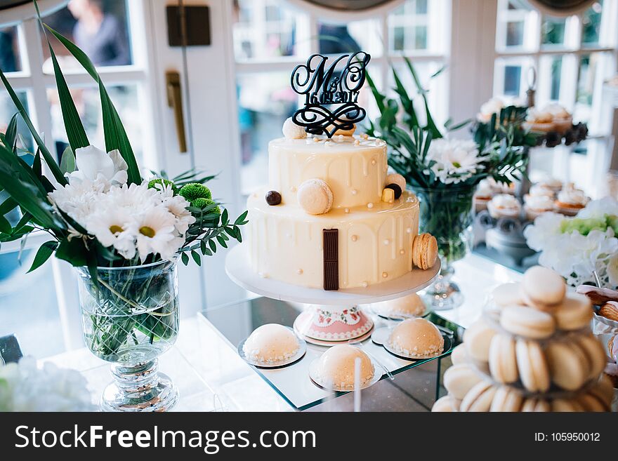 Candy bar and wedding cake with flowers. Table with sweets, buffet with cupcakes, candies, dessert.