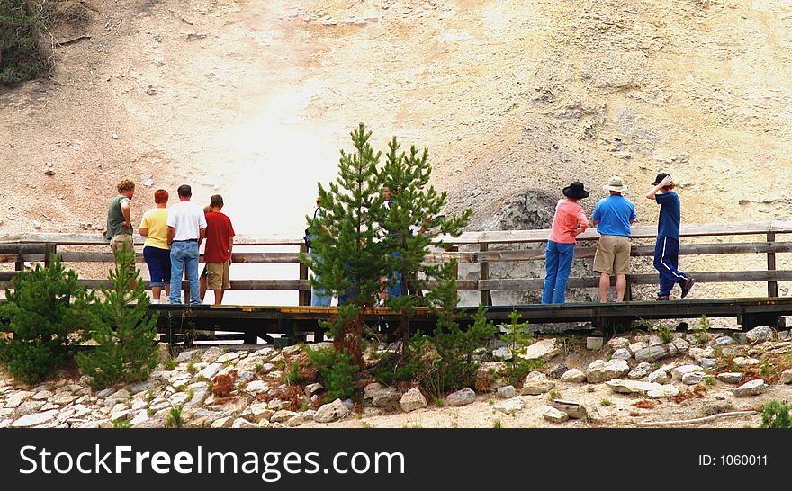 Tourists sightsee rock formations and geysers on a boardwalk. Tourists sightsee rock formations and geysers on a boardwalk.