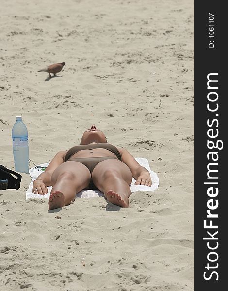 Woman sunbathing, with a cool bottle of water by her side