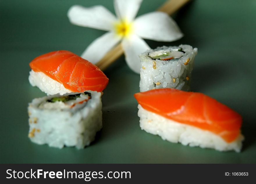 A plate of sushi with chopsticks and plumeria flower. A plate of sushi with chopsticks and plumeria flower