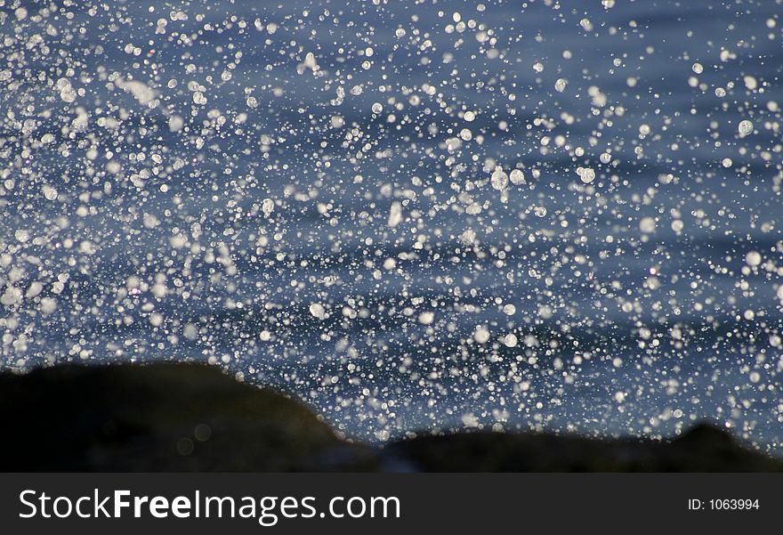 Close-up of sea spray over shoreline lava rocks