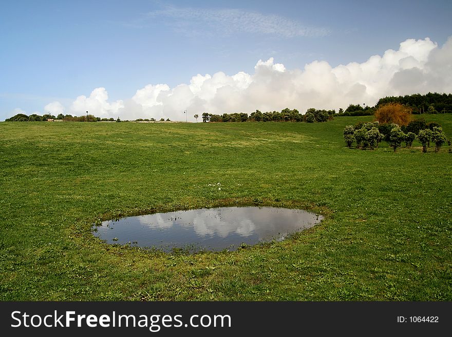 Green field - Landscape green grass, blue sky, white clouds and a lake