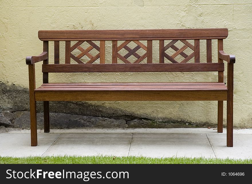 Wooden Park bench against textured yellow wall