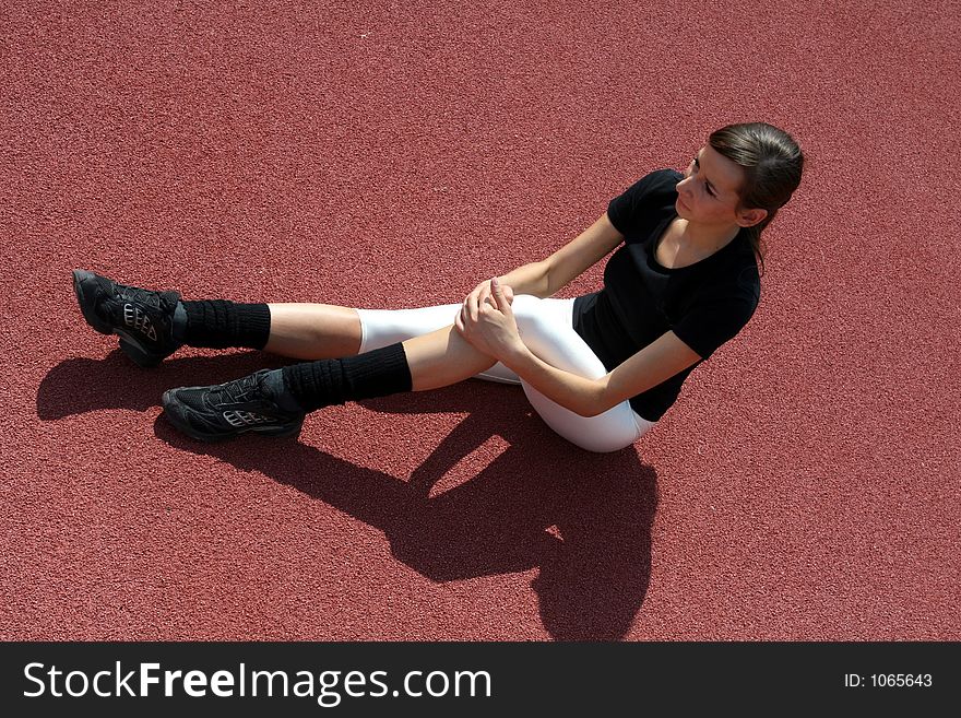 A young girl stretching on the track. A young girl stretching on the track