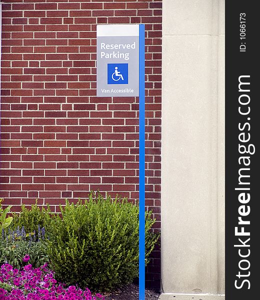 Handicaped parking sign outside of a brick building.