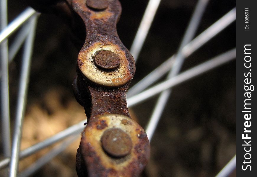 Up close of a rusted bike chain with the spokes in the background