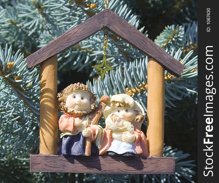 Jesus, Mary and Joseph sit inside the frame of a building, with a Gold star over their heads. This special ornament is hanging on a fir tree. Jesus, Mary and Joseph sit inside the frame of a building, with a Gold star over their heads. This special ornament is hanging on a fir tree.