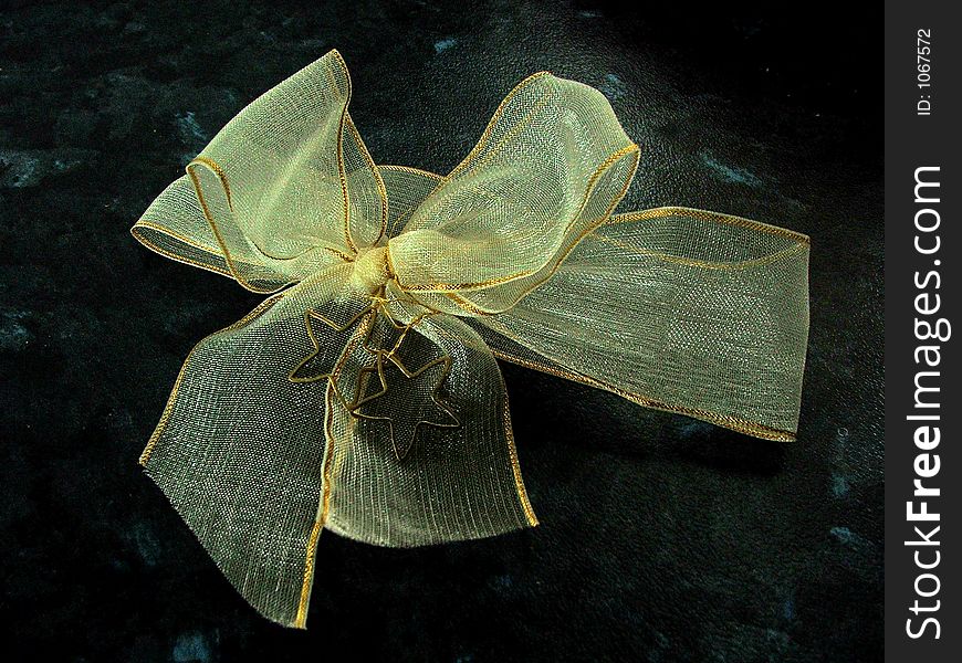 Decorative bow from gauze with two gold metal stars and gold trim. Decorative bow from gauze with two gold metal stars and gold trim