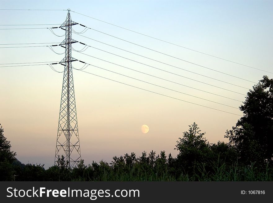 Mast and power lines with moon in the background