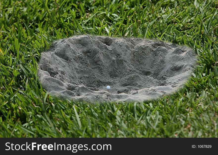 Golf ball in a hole of sand with grass