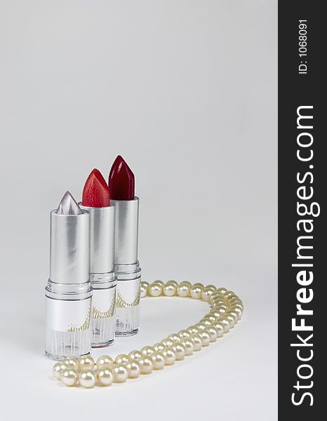Red and silver Lipstick with a pearl necklace on a silver background. Red and silver Lipstick with a pearl necklace on a silver background