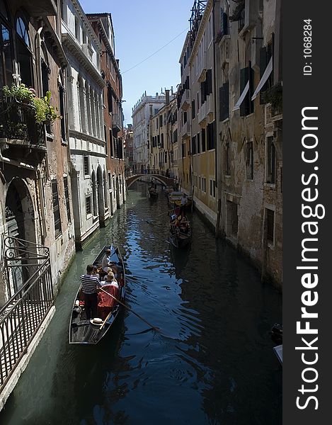 A canal in venice with gondolas and tourists. A canal in venice with gondolas and tourists