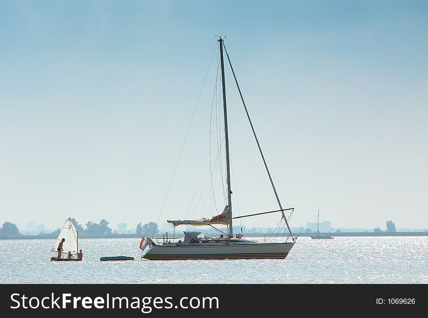 A very small and a big sailboat. A very small and a big sailboat