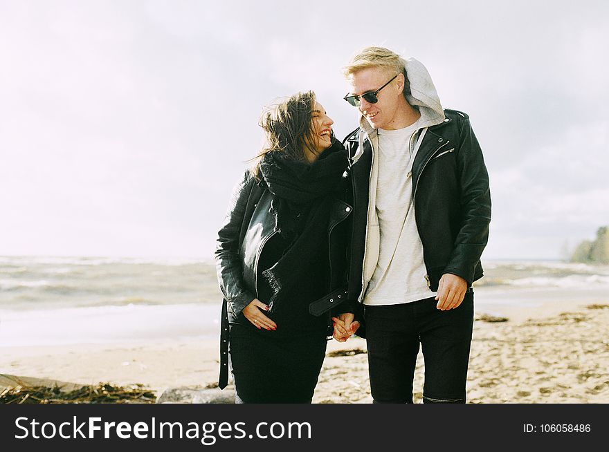Man and Woman Wearing Jackets Near Seaside Under Cloudy Sky