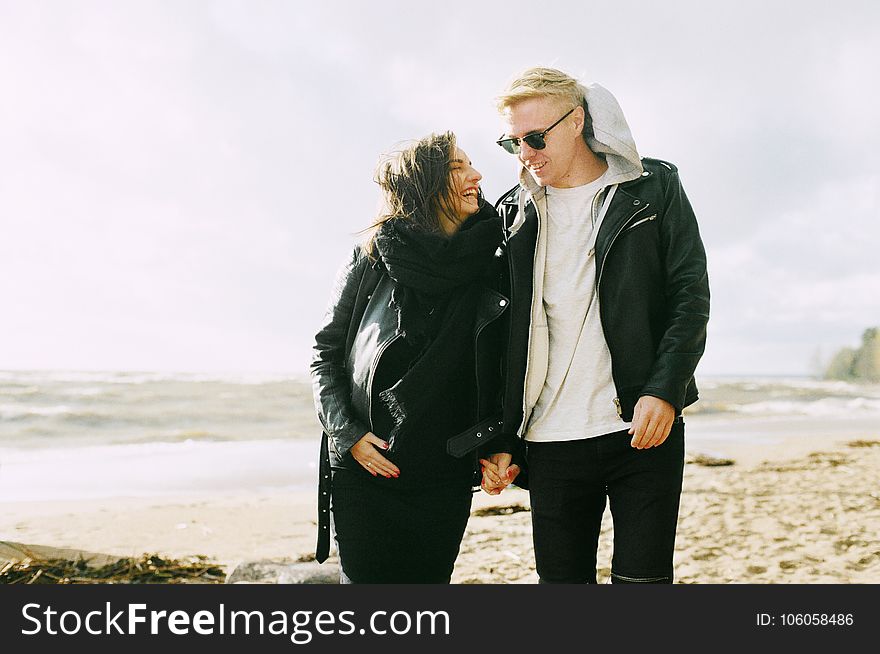 Man And Woman Wearing Jackets Near Seaside Under Cloudy Sky