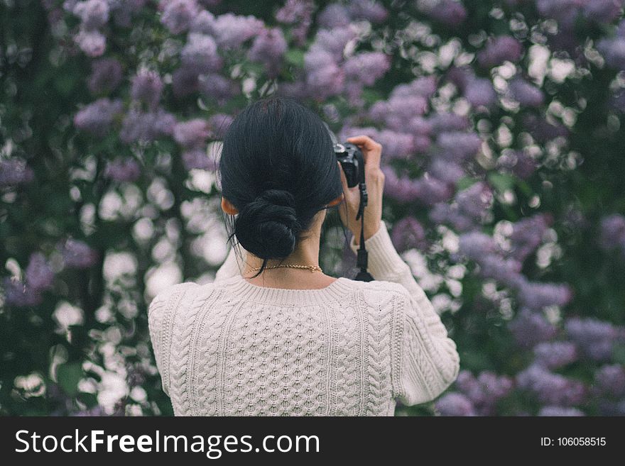 Woman Holding Camera Taking Photos of Flowers