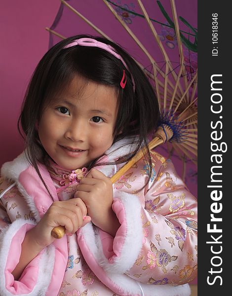 Cute little asian chinese girl with a umbrella in a beautiful pink dress. Cute little asian chinese girl with a umbrella in a beautiful pink dress