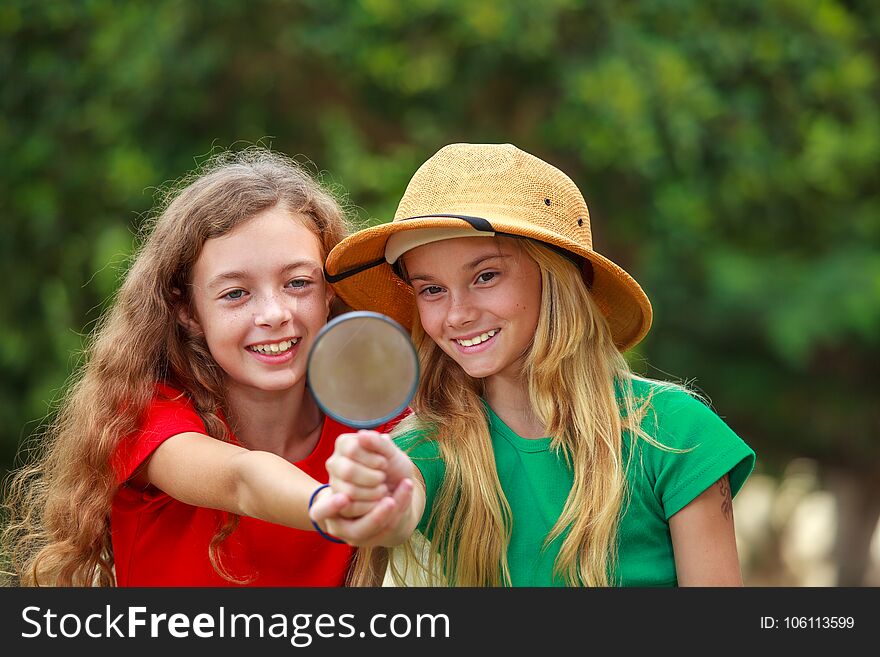 Two school girls exploring the nature with magnifying glass