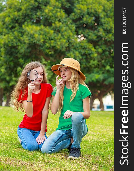 Two school girls exploring the nature with magnifying glass