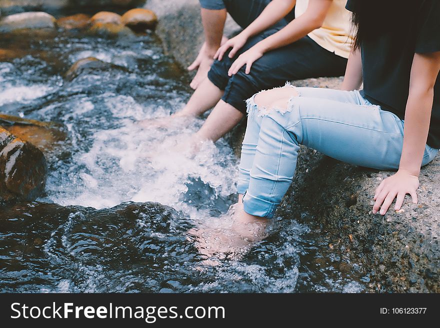 People In Jeans With Feet In Water