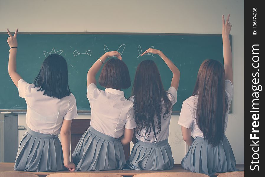 Photo of Four Girls Wearing School Uniform Doing Hand Signs