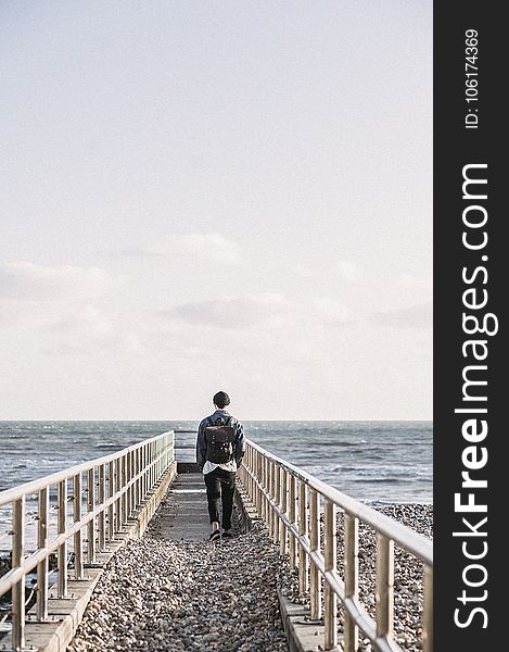 Man In Black Jacket Walking On Gray Concrete Dock