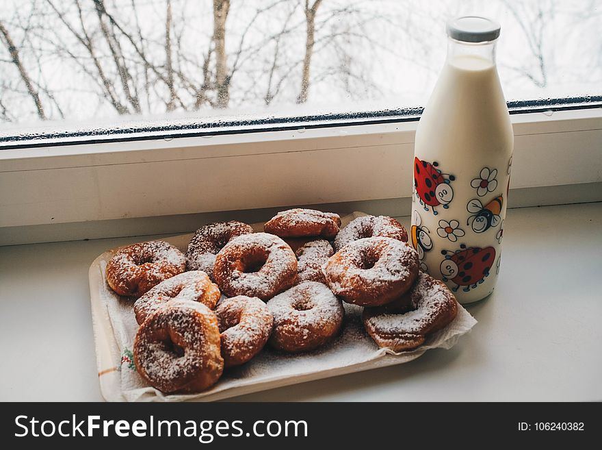 Doughnuts and Milk Bottle Near Clear Glass Window