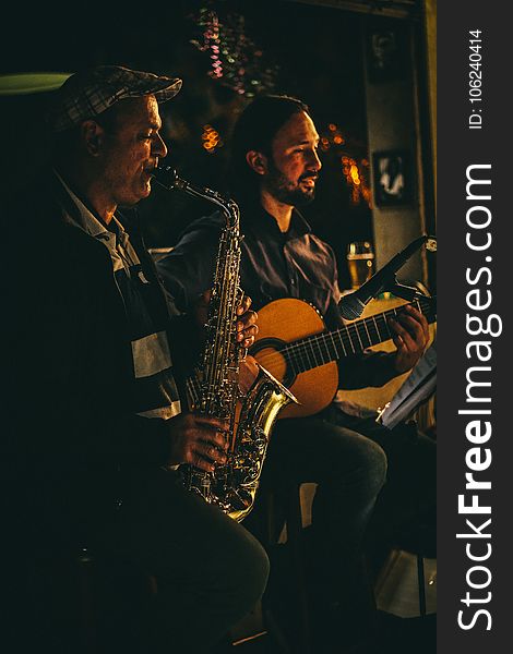 Two Men Playing Saxophone and Acoustic Guitar during Night Time