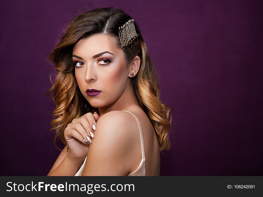 Girl With Golden Curly Hair And Hairpins Posing In Front Of Purple Wall