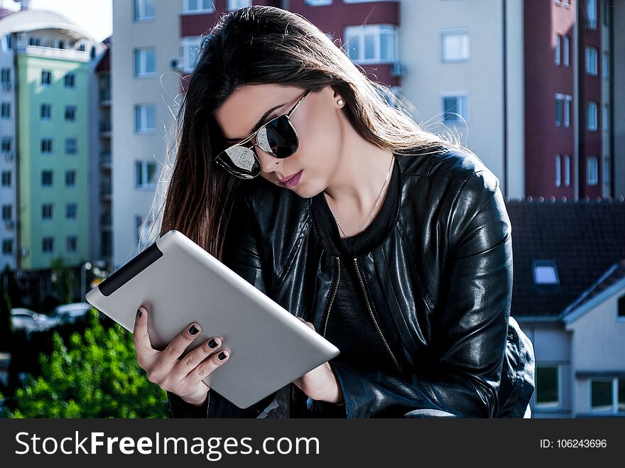 Beauty girl reading news on the tablet on a beautiful spring day outside