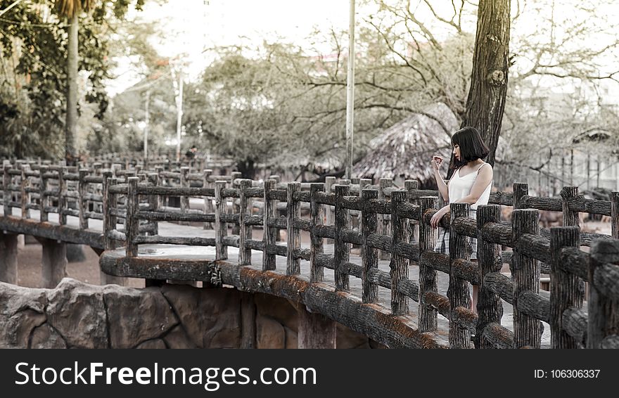 Woman in White Shirt Standing on Black Bridge
