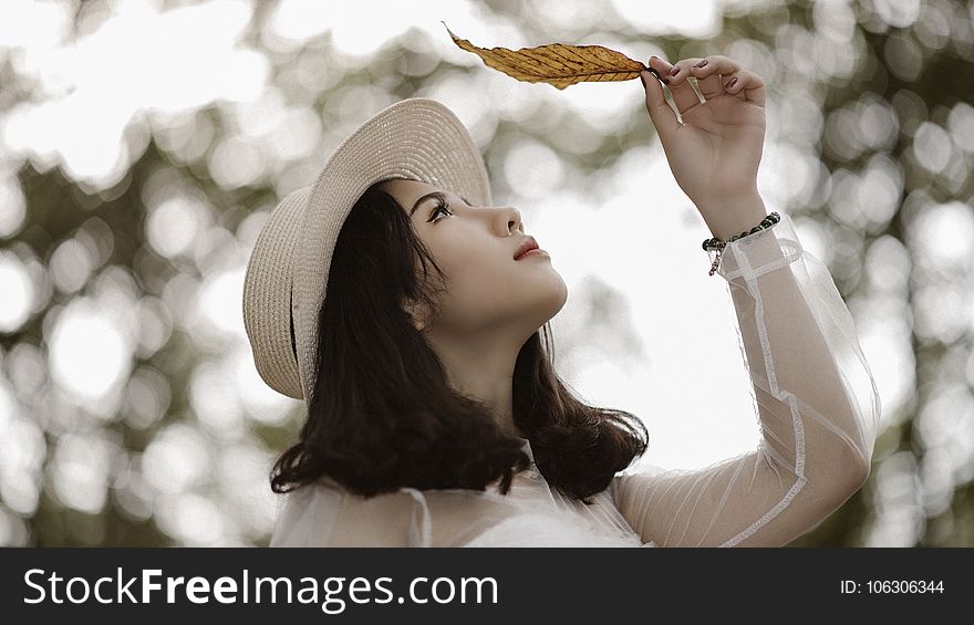 Woman Wearing White Long Sleeve Scoop-neck Top While Holding Brown Leaf