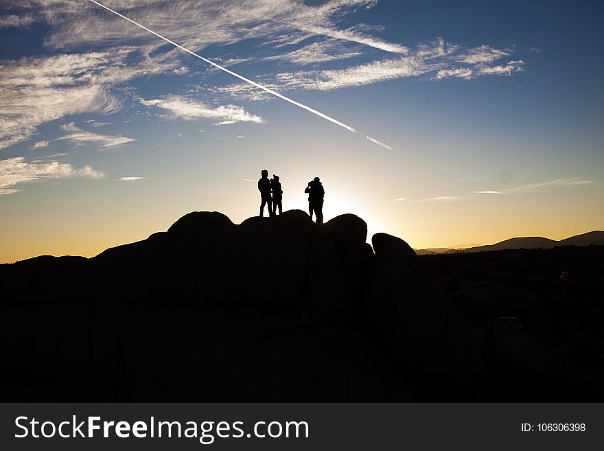 Silhouette Photo of People on Top of Rock Formation