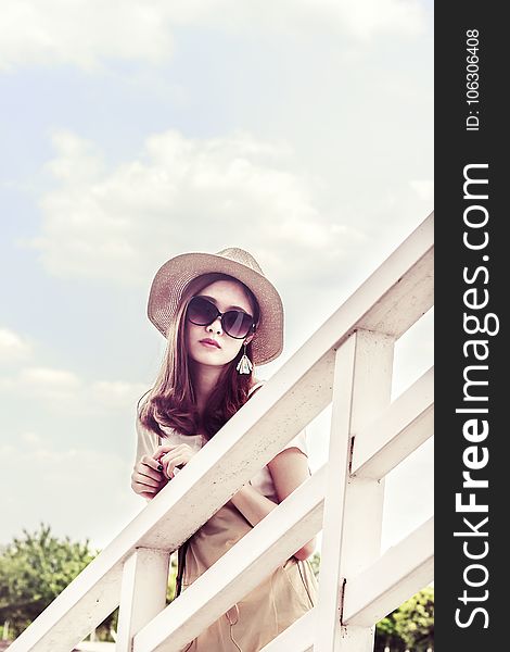 Woman Wearing Gray Sun Hat in Front of White Fence