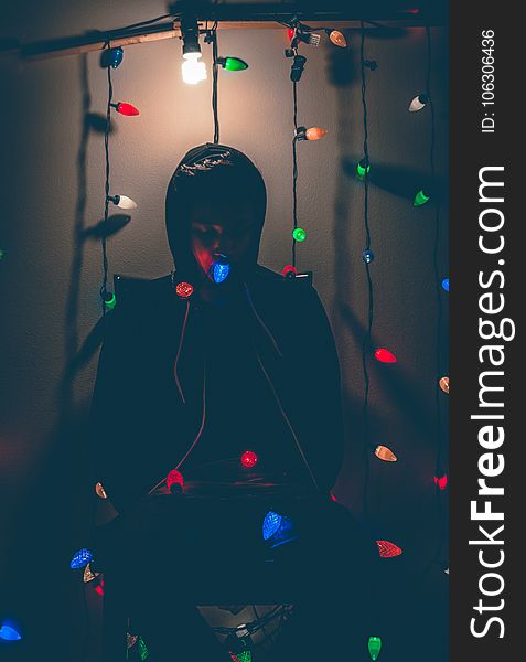 Man Sitting on Chair With Multi-colored String Lights