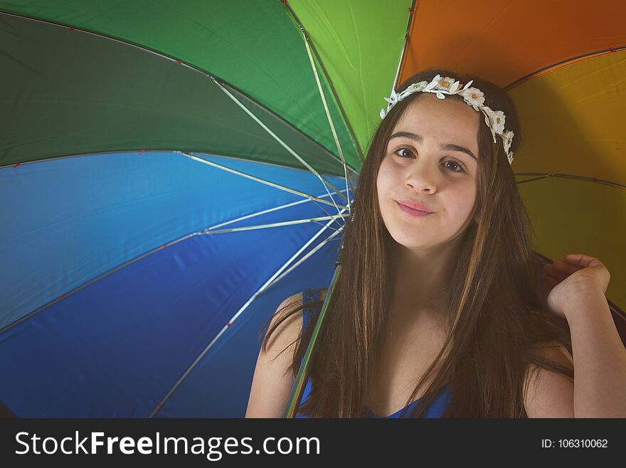 A nice little girl with daisy crown is holding a colored umbrella. A nice little girl with daisy crown is holding a colored umbrella