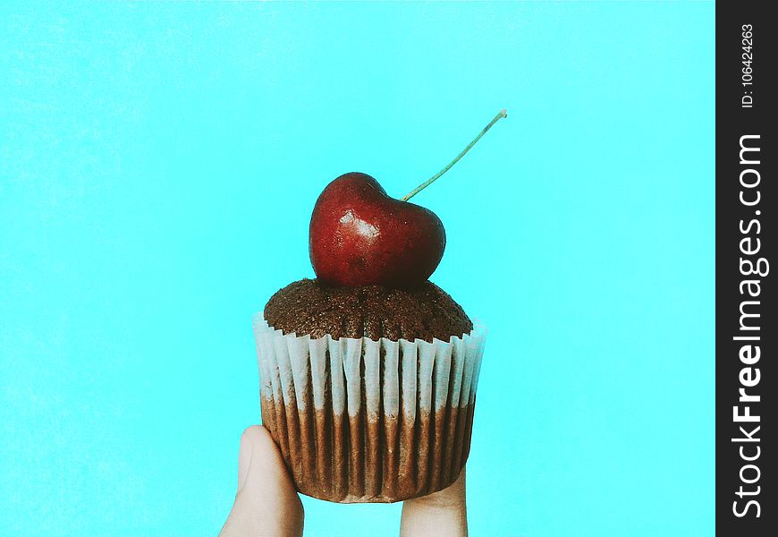 Person Holding Chocolate Cupcake With Cherry Topping