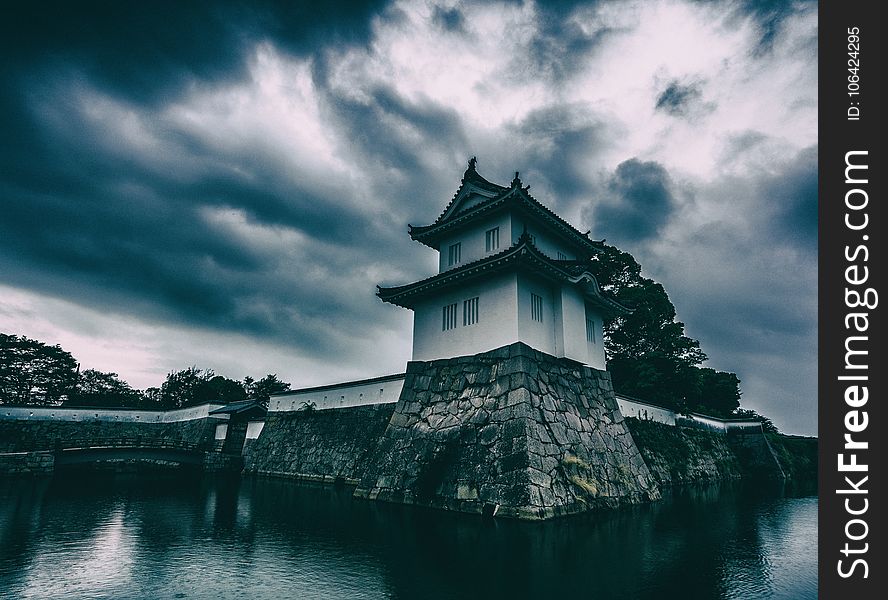 White and Black Concrete Building Near Body of Water Under Gray Cloudy Sky