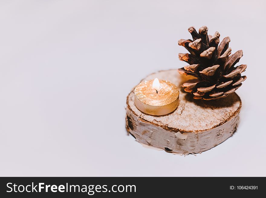 Brown Pine Cone Nut Beside Tealight Candle