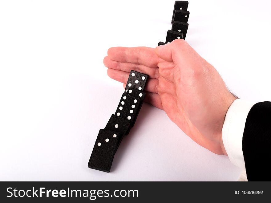 Businessman Hand Stopping Dominoes Row From Falling On White Table