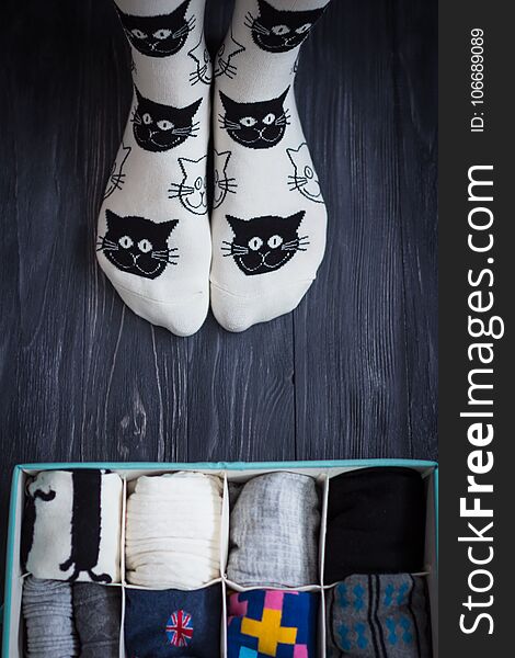 Feet selfie with black and white socks and a socks organizer on a dark wooden background. Top view