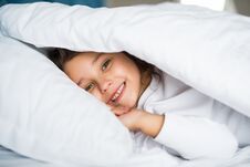 Pretty Little Girl In Sleepwear Lying Under Blanket In The Bed At Home Stock Photo