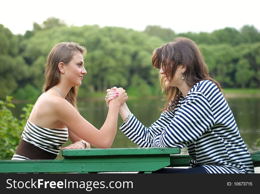 Two girls doing arm-wrestling outdoors. Two girls doing arm-wrestling outdoors